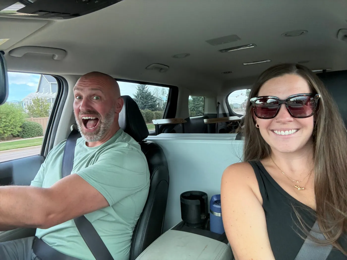Michael making a goofy face while driving, with Alyssa smiling in the passenger seat
