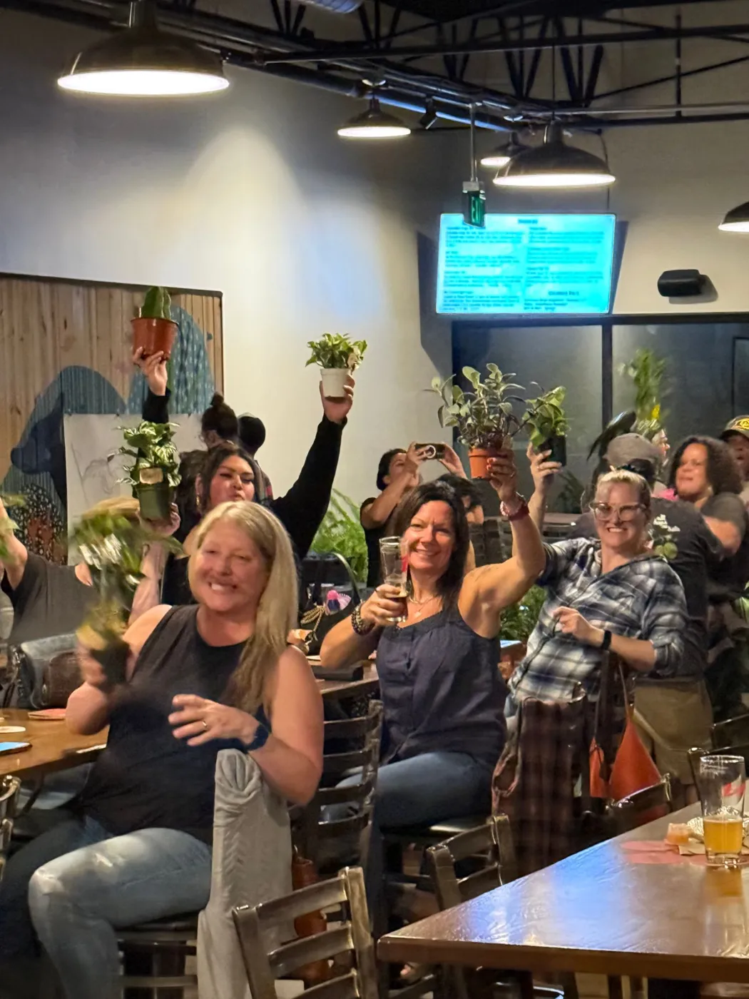 Players at a long table cheering and raising plants and glasses