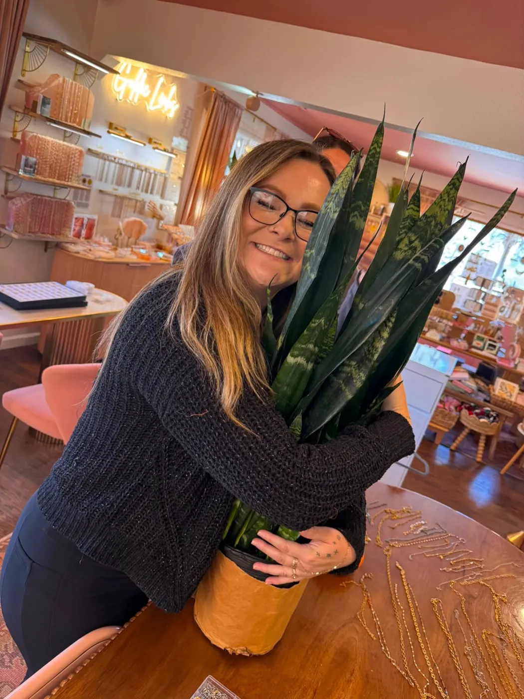 A happy customer hugging a tall snake plant at Goldie Links
